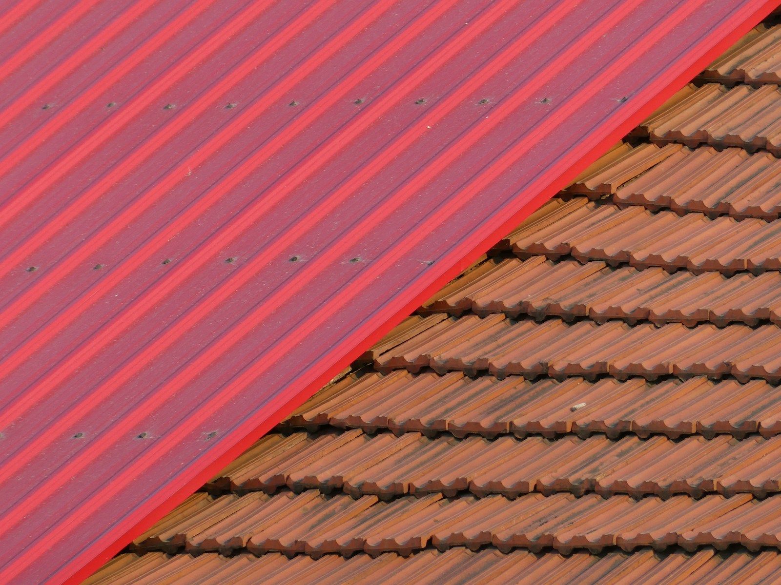 Spoj crvenog trapeznog lima i crepa na krovu