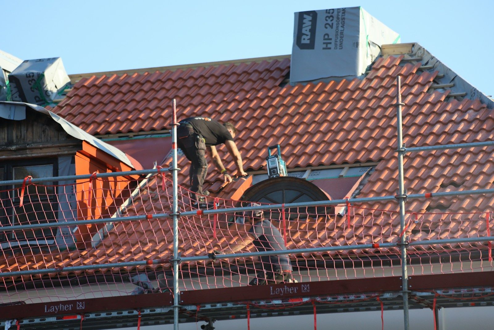 Majstor na krovu od crepa, sa skelom i zaštitnom ogradom